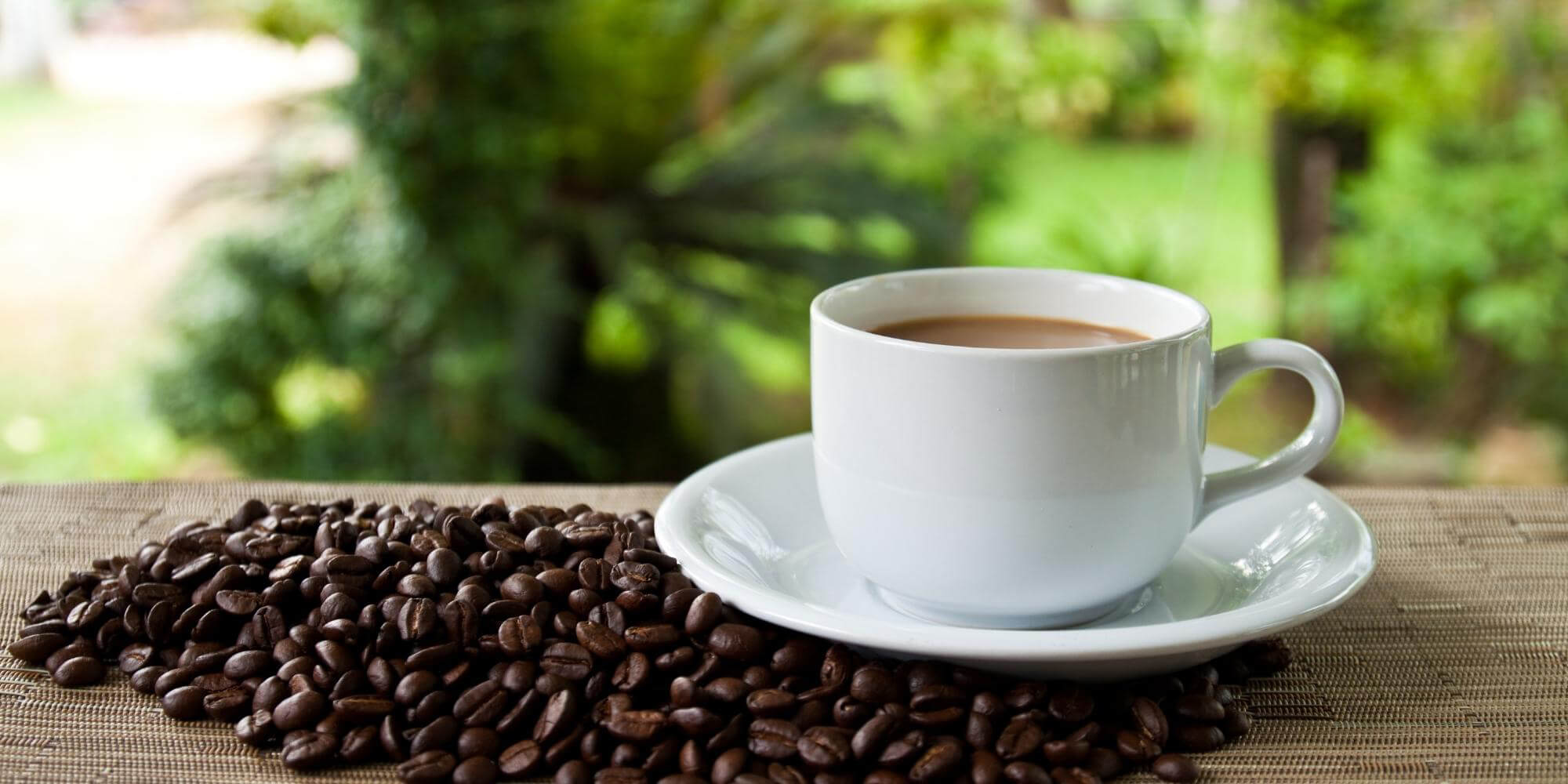Eine Tasse Kaffee mit ganzen Kaffeebohnen auf einem Tisch 