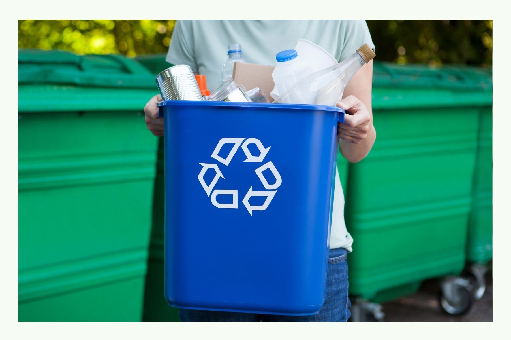 Person holding a blue recycling bin with symbol